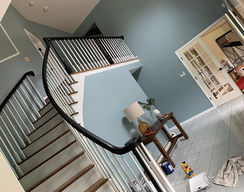 Painted stairwell and hallway with white and black railings and blue walls